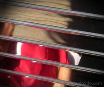 Reflejo fragmentado de una persona con prenda roja entre franjas horizontales